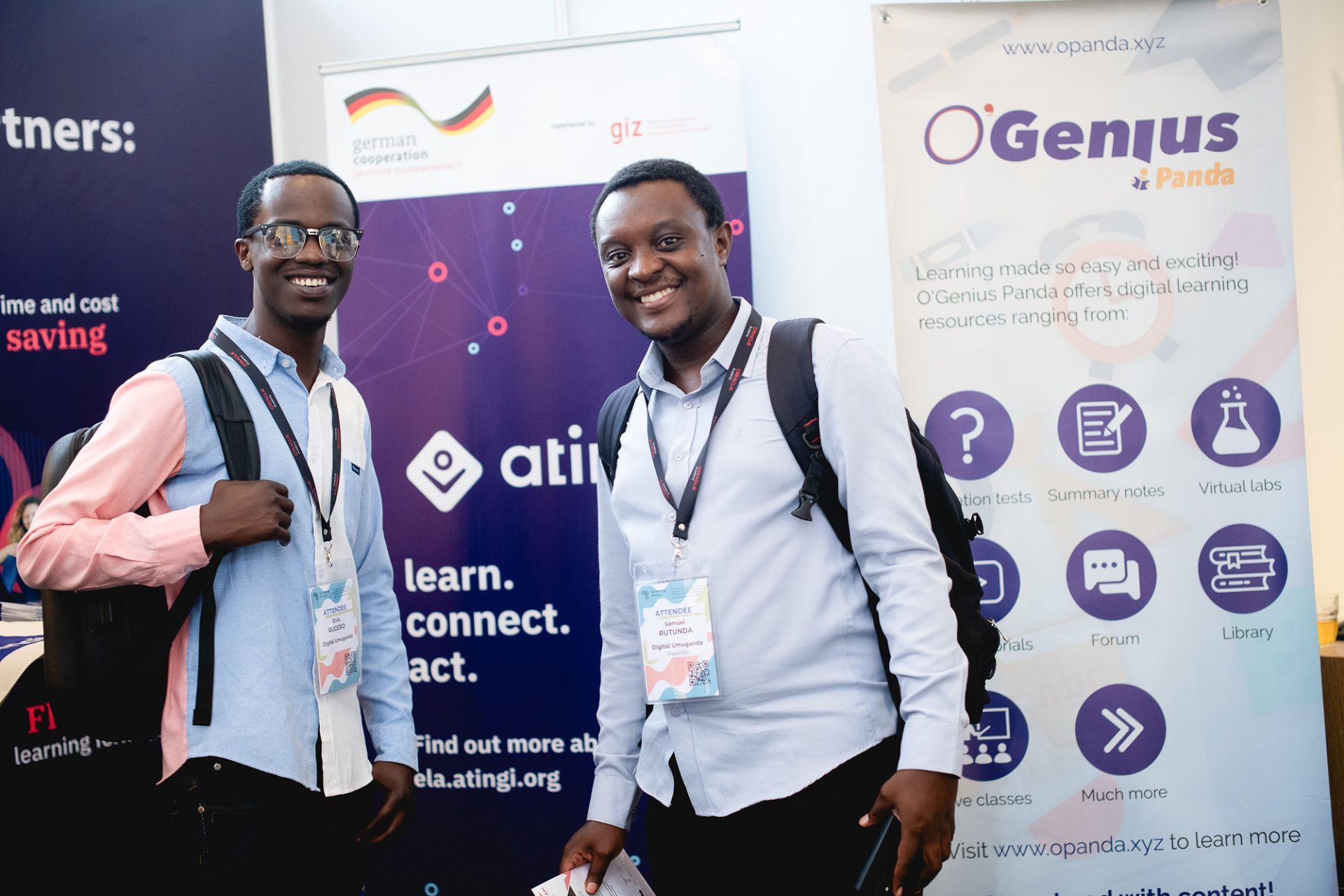 Two man with conference badges in front of roll-up banners at an e-learning conference.