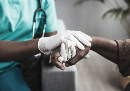 A nurse holding a patients hands.